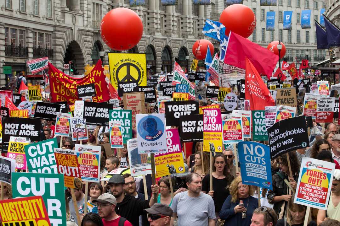 Image of people at UK anti-austerity protest holding picket signs